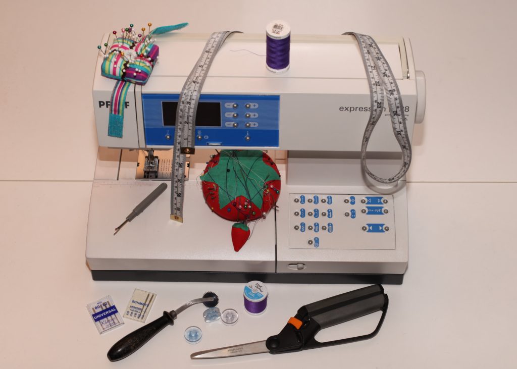 Sewing Notions Still Life a "still life" Photo of a bunch of sewing notions, including a sewing machine, scissors, tape measure and pins. Items you will want if you start sewing clothes.